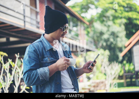 Hipster man resting at home balcony with the coffee cup in hand, Relaxing holiday concept. Stock Photo