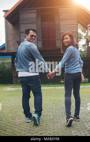 Close-up of loving couple holding hands while walking outdoor, Looked back and smile to camera, Couple in love concept. Stock Photo