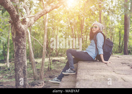 Young attractive woman resting with backpack while going to ancient phanom rung temple in thailand. Stock Photo