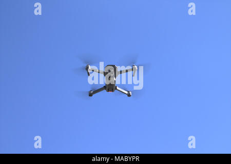 DJI Mavic Pro drone with 4k camera mounted on a 3 axis mechanical gimbal coming in to land against a clear blue sky. Stock Photo