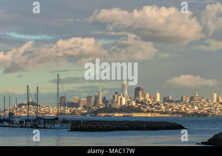 Sailboats dock at the marina in Sausaiito, with the city of San Francisco lit up by the evening light in the background, California, United States. Stock Photo