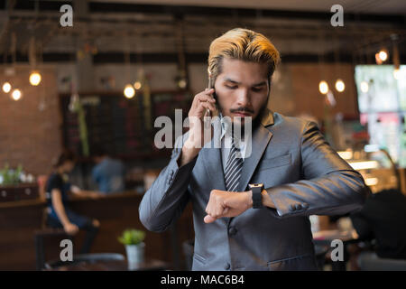Businessman talking on phone looking at hand watch. Have meeting soon. Stock Photo