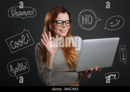 Cheerful person waving and smiling while having a video call Stock Photo