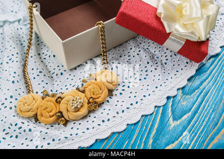 Handmade peach-colored necklace on a chain lies close to the gift box Stock Photo