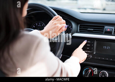 Woman pressing radio button on car's control panel Stock Photo