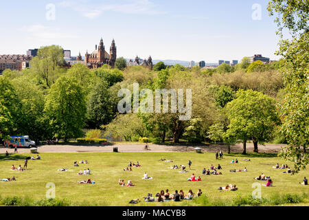 Young people, students of the University of Glasgow enjoying a warm sunny day on the lawns of Kelvingrove park, Kelvingrove Art Gallery and Museum in  Stock Photo