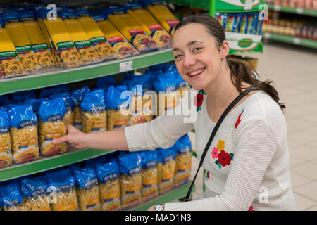 Beautiful middle-aged woman choosing spaghetti in a store. Woman with a package pasta in the shop. Stock Photo