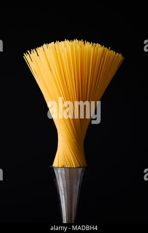 spaghetti pasta as a modern design artwork on a steel pedestal and resembling a brush, food concept. Stock Photo