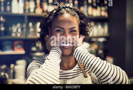 Young African female entrepreneur leaning on a counter while standing in of her trendy cafe Stock Photo