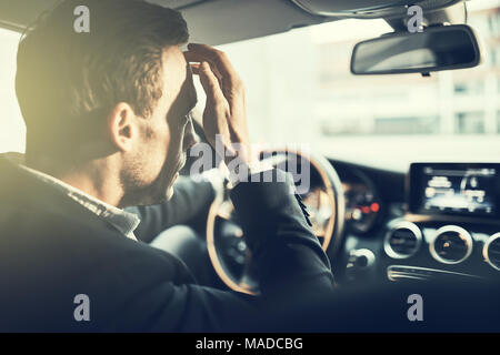 Rearview of a young businessman looking stressed while driving his car in traffic during his morning commute to work Stock Photo