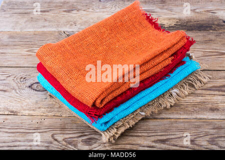 Stack of colored  burlap on wooden table. Studio Photo Stock Photo