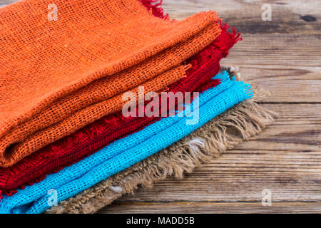Stack of colored  burlap on wooden table. Studio Photo Stock Photo