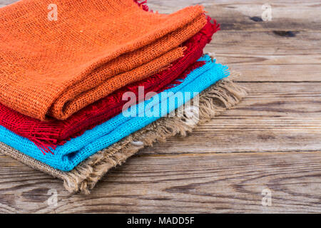 Stack of colored  burlap on wooden table. Studio Photo Stock Photo