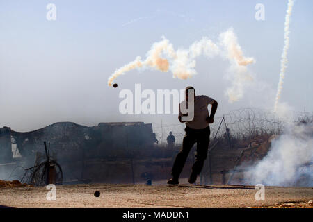 Bilin, Palestine, December 3, 2010: Protester escapes tear gas grenade by a security fence during weekly demonstrations against Palestinian land confi Stock Photo