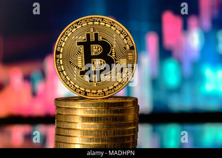 Bitcoin on top of Money stack, against blurry background Stock Photo