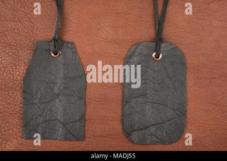 Two blank black leather tag label on brown leather. View from above Stock Photo