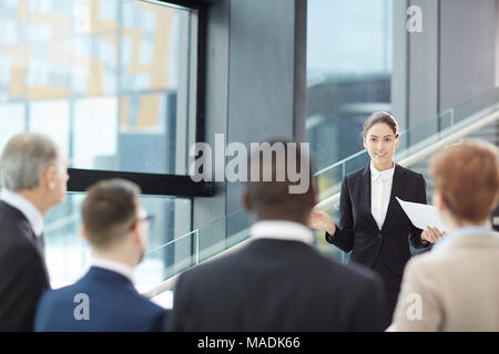 Young elegant businesswoman making report for her colleagues during or before conference Stock Photo