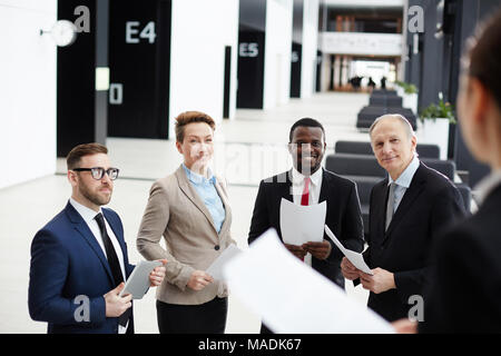 Intercultural business group looking at speaker explaining them points of successful speech at conference Stock Photo