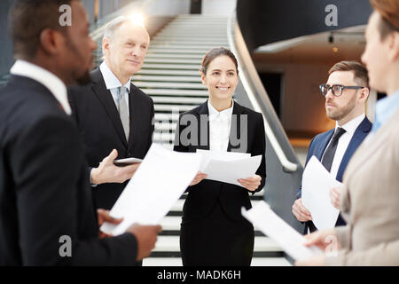 Confident delegates or employees in formalwear discussing their reports while preparing for conference Stock Photo