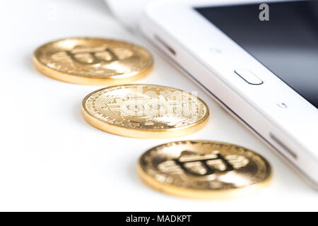 Bitcoins on a white table next to the tablet Stock Photo