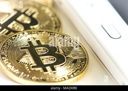 Bitcoins on a white table next to the tablet Stock Photo