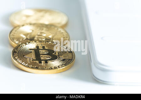 Bitcoins on a white table next to the tablet Stock Photo