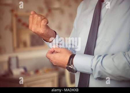 Male hands fixing stylish silver cufflinks on blue shirt cuffs sleeves in formal suit Stock Photo