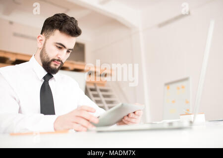 Young businessman sitting at the table and using digital tablet Stock Photo