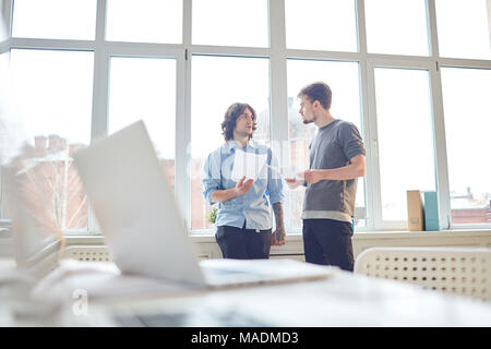 Two business partners standing at office and discussing business reports Stock Photo