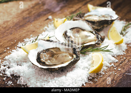 fresh just opened oysters and slice of lemon on rustic wooden background Stock Photo