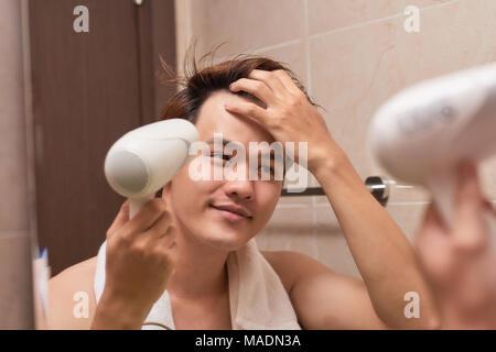 Young asian man blow drying hair in bathroom Stock Photo - Alamy