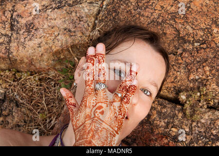 girl taking selfie laying on the ground with her henna tattoo Stock Photo