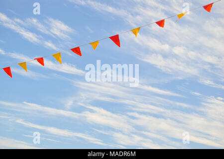 Multi-colored triangular flags isolated against a sky with clouds Stock Photo