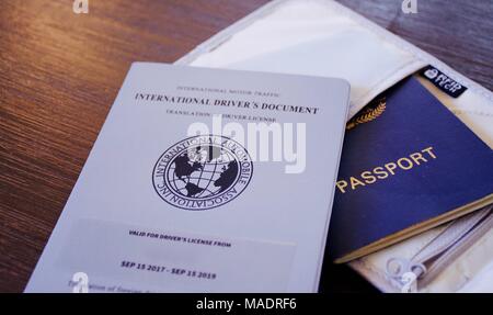 Blue passport with international drivers licence in a RFID travel pouch on a dark wooden background Stock Photo
