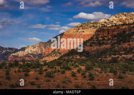 Colorful view of red rock formations cascading into the distance from Vultee Arch hiking trail on a sunny day with blue sky and clouds, Sedona, Arizon Stock Photo