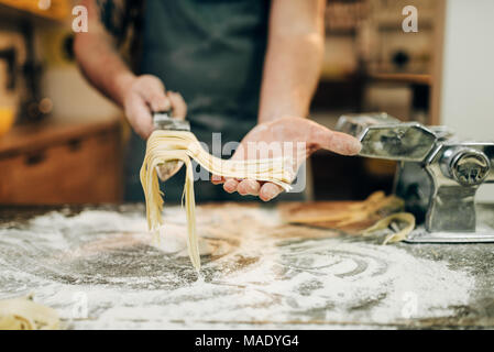 Chef cooking fettuccine in pasta machine Stock Photo