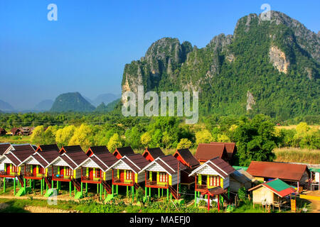 Row of tourist bungalows along Nam Song River in Vang Vieng, Vientiane Province, Laos. Vang Vieng is a popular destination for adventure tourism in a  Stock Photo