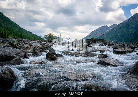 Clear river with rocks leads towards mountains Stock Photo