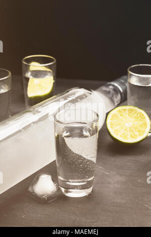 Cold vodka in shot glasses on a black background. Toned Stock Photo