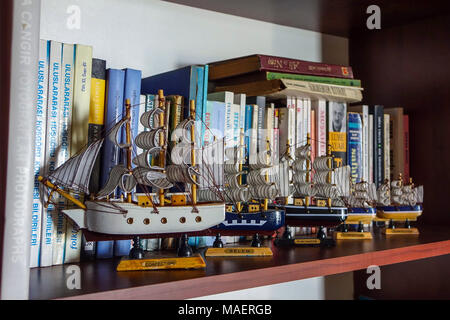 Line of four small model sailing ships on book shelf, Antalya, Turkey Stock Photo