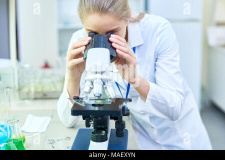 Busy female biologist using microscope in lab Stock Photo