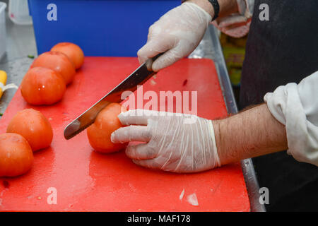 Cutting tomatoes - male hands with gloves cutting a tomato Stock Photo