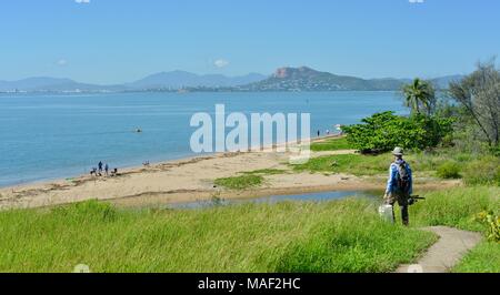 Fisherman walking down a path with a view of castle hill from pallarenda, Shelly Cove trail at Cape Pallarenda Conservation Park Queensland Australia Stock Photo