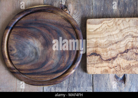 Chopping boards of different shapes on a wooden background. Round and square of olive wood. View from above. Stock Photo