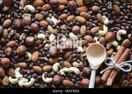 Different nuts on a wooden table. Cedar, cashew, hazelnut, walnuts and a spoon on the table. Many nuts are inshell and chistchenyh on a wooden backgro Stock Photo