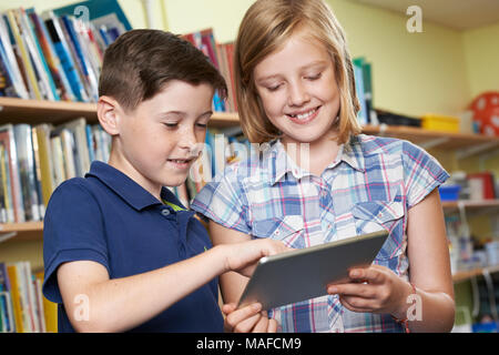 Pupils Using Digital Tablet In School Library Stock Photo