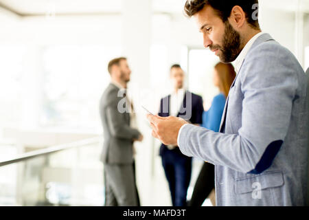 Handsome young businessman using mobile phone in office Stock Photo