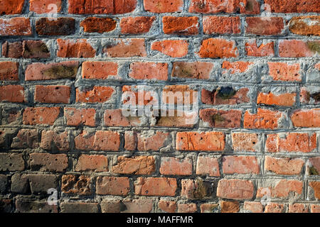 Uneven wall of old burned red brick Stock Photo