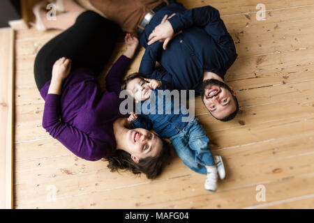 Mother father and little son studio portrait from up. Happy family lay at floor. Stock Photo