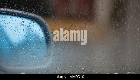 Car mirror behind a transparent window with raindrops. Abstract, blurred background, space for text Stock Photo